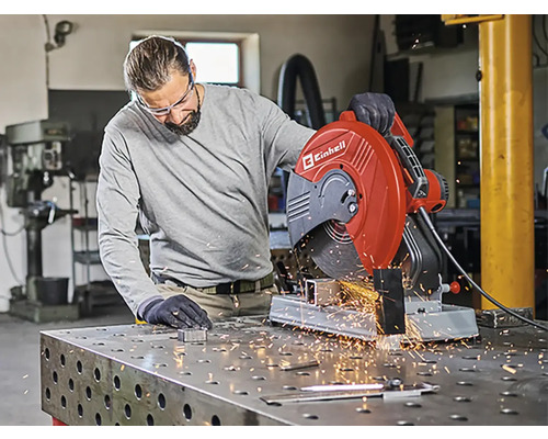 Muž obsluhuje rozbrušovací pilu Einhell v dílně, létají jiskry.