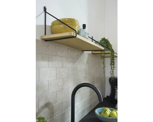 Police s dřevěnými deskami a černým držákem na obkládané zdi v kuchyni.