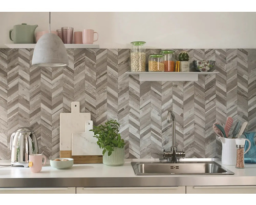 Kuchyňská scéna s dřezem, baterií, kuchyňským náčiním a policemi před stěnou se vzorem rybí kosti