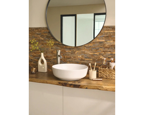 Koupelna s kulatým zrcadlem, umyvadlem na desku, vodovodní baterií a dekorací na dřevěné desce