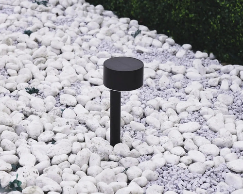 Černé solární svítidlo v zahradě mezi bílými kameny