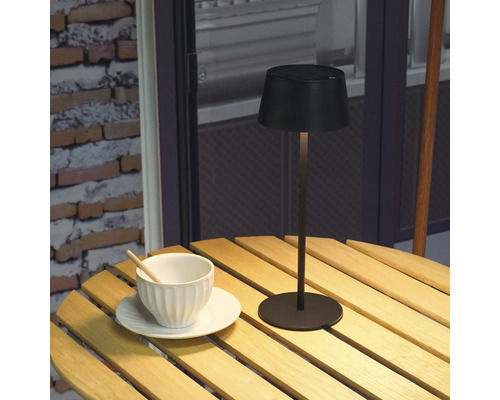 Solární lampa na dřevěném stole s šálkem a podšálkem