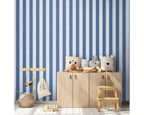 Dětský pokoj s pruhovanou tapetou, dřevěnou komodou a hračkami.