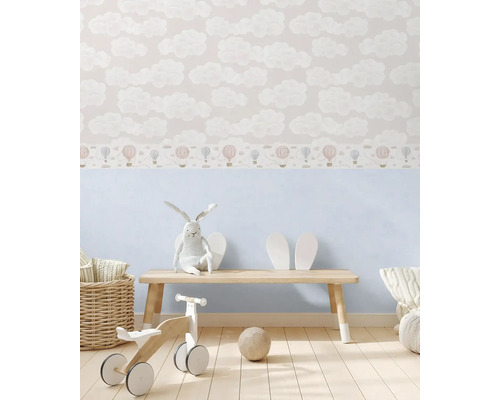 Dětský pokoj s tapetou se vzorem mraků a balónků, dřevěná lavice, plyšový zajíc a dřevěné hračky