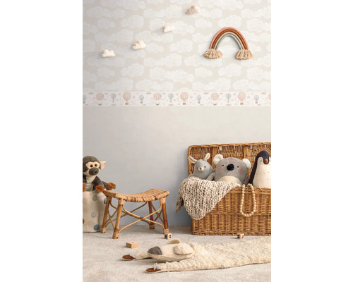 Dětský pokoj s tapetou s motivem mraků, hračkami a ratanovým nábytkem pro útulnou atmosféru