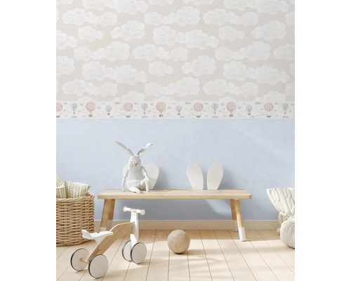 Dětský pokoj s tapetou s motivem oblaků a horkovzdušných balónů, dřevěnou lavicí a hračkami