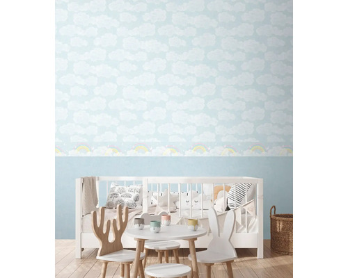 Dětský pokoj s tapetou s motivem oblaků a dětským nábytkem.