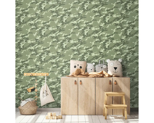 Zdobený dětský pokoj s tapetou se vzorem kamufláže, dřevěnou skříňkou, ozdobnými polštáři, úložným košem a hračkami