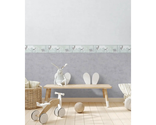 Dětský pokoj s bordurou na tapety s ilustracemi zvířat, dřevěnou podlahou a hračkami.