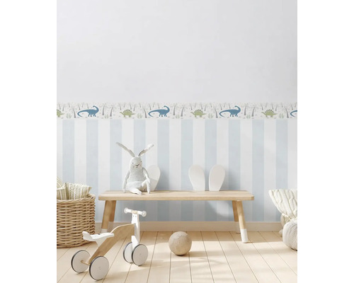 Světlý dětský pokoj s pruhovanou tapetou, dinosauří bordurou, dřevěnou lavicí, hračkami a košíkem
