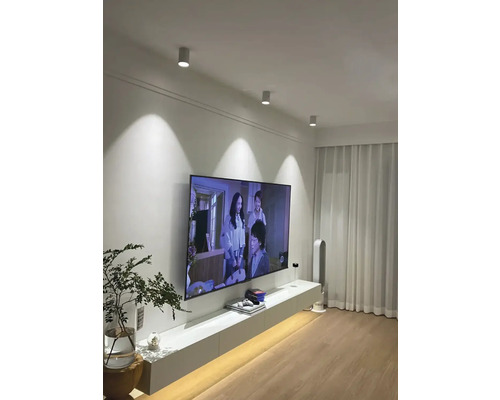 Obývací pokoj se stropními svítidly, televizorem a bílým nábytkem