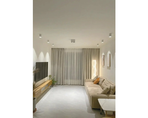 Světlý obývací pokoj s pohovkou, závěsy a televizí