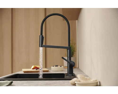 Černá kuchyňská baterie s tekoucí vodou v moderní kuchyni.