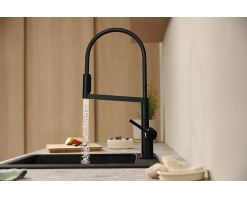 Černá kuchyňská baterie s proudem vody nad dřezem