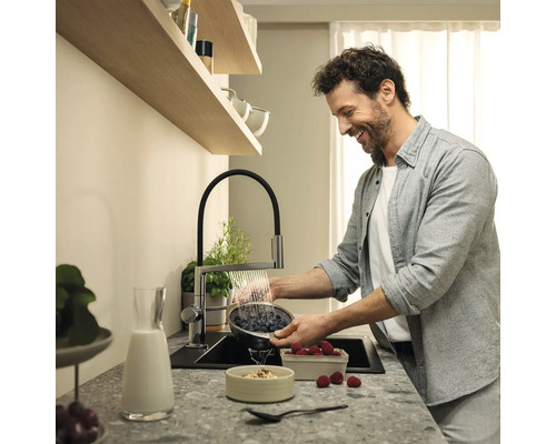 Muž myje bobule v umyvadle s kuchyňskou baterií