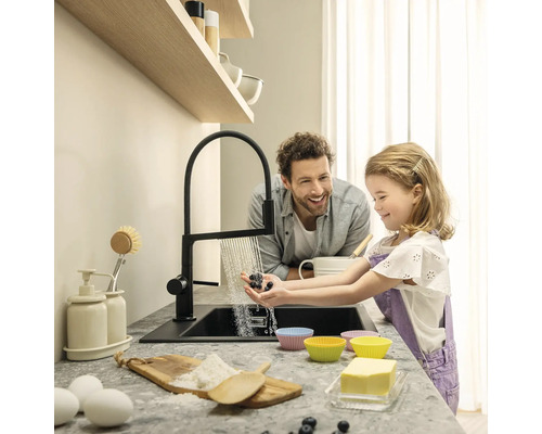 Kuchyňská scéna s otcem a dcerou myjícími bobule u dřezu, s moderní baterií a ingrediencemi na pečení na pracovní desce.