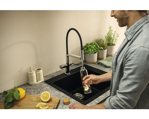 Černý dřez s kohoutkem, bylinkami a citronem v kuchyni