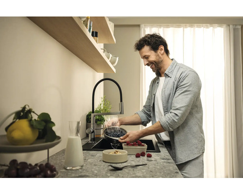 Muž myje bobule v kuchyňském dřezu s kuchyňskou baterií.