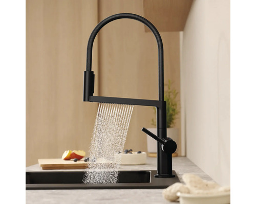 Černá kuchyňská baterie s proudem vody v umyvadle