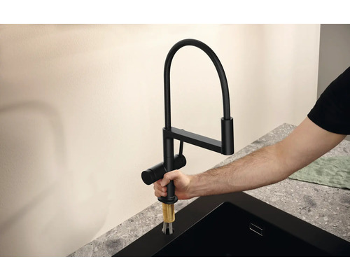 Černá kuchyňská baterie s flexibilním výtokem je montována.