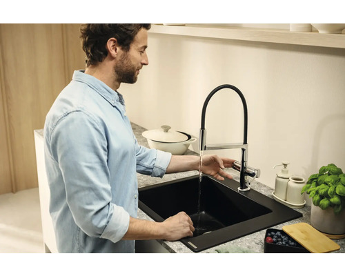 Muž u umyvadla s vodovodní baterií a dřezem v kuchyni.