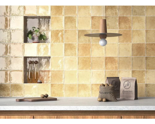 Kuchyňská stěna obložená čtvercovými dlaždicemi, police, dekorace a potraviny