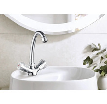 Lesklá vodovodní baterie s transparentními rukojeťmi na bílém umyvadle