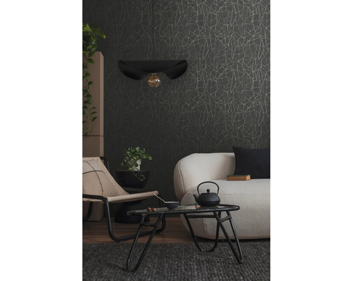 Obývací pokoj s pohovkou, křeslem, stolem, závěsnou lampou a vzorovanou tapetou.