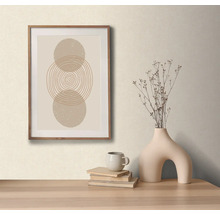 Dekorativní aranžmá s zarámovaným obrazem s abstraktním kruhovým motivem, váza se suchými květinami, šálek a knihy na stole.