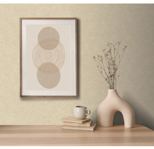 Dekorativní scéna s abstraktním uměleckým dílem v rámu, vázou s květinami, knihami a šálkem na stole.