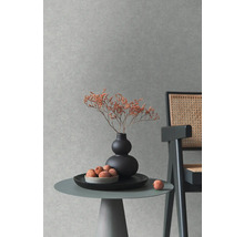 Dekorativní scéna se stolem, vázou, sušenými květinami a židlí před strukturovanou stěnou