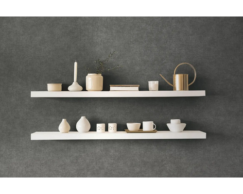 Dvě bílé nástěnné police s dekorativními předměty na tmavé stěně