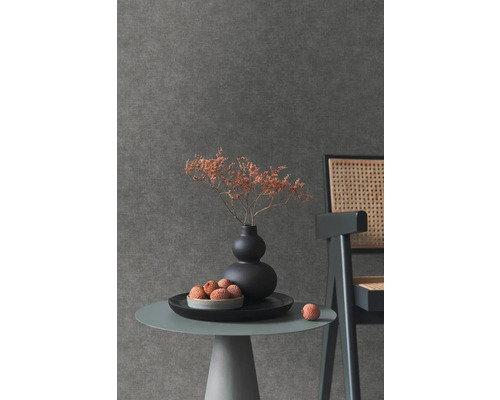 Detail stolu s dekorací před tmavou tapetou.