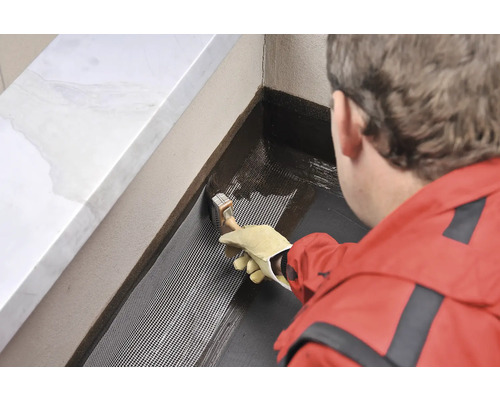 Osoba nanáší štětcem těsnicí hmotu na tkaninu