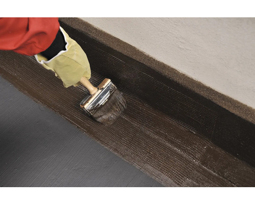 Nanášení těsnicího materiálu štětcem na zeď.