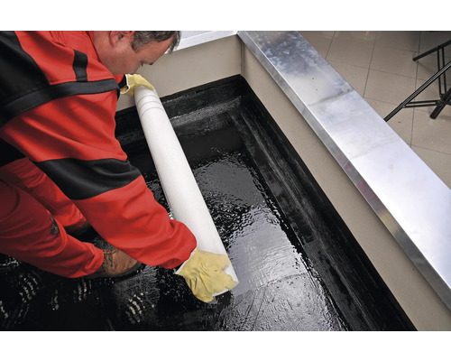 Řemeslník pokládá hydroizolační pás na střešní terasu