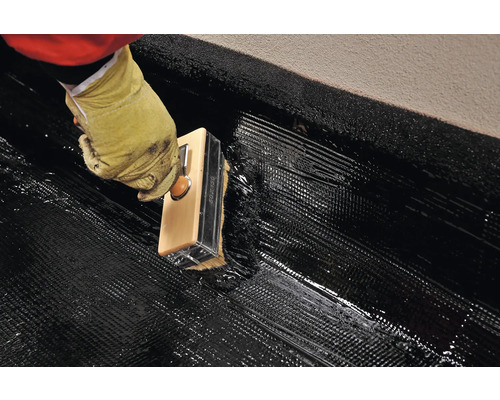 Nanášení bitumenové hydroizolace štětcem na povrch.