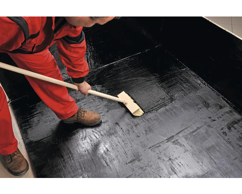 Osoba nanáší vodotěsný nátěr pomocí štětky.