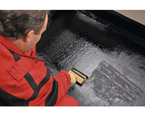 Osoba nanáší nátěr štětcem na povrch.