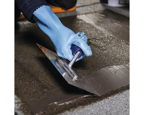 Osoba nanáší stěrkou povrchovou úpravu.