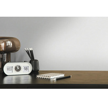 Dekorativní pokoj s hodinami, tužkami, poznámkovým blokem a lampou na tmavém dřevěném stole před jednobarevnou zdí.