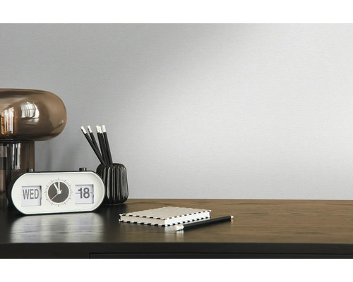 Dekorativní pokoj s hodinami, tužkami, poznámkovým blokem a lampou na tmavém dřevěném stole před jednobarevnou zdí.