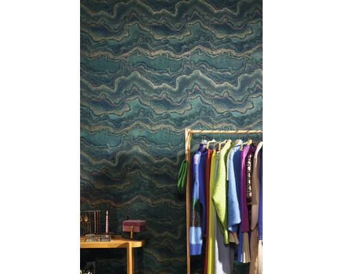Bytová scéna se zelenou vliesovou tapetou s vlnkovým vzorem, věšákem na šaty a doplňky