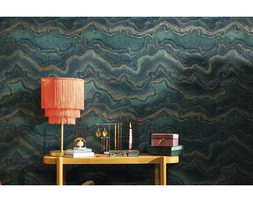 Scéna s vzorovanou tapetou, stolem a dekorativními předměty, jako je lampa, stojan na šperky a svíčka