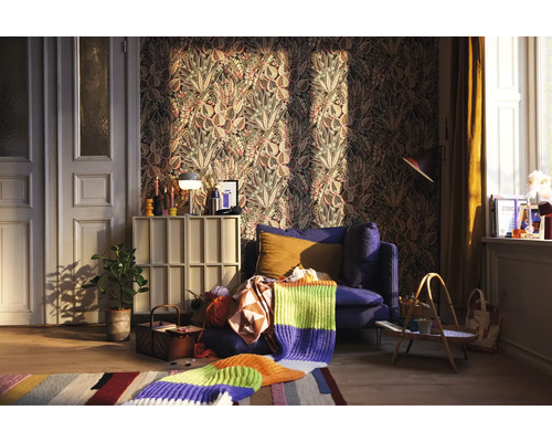 Obývací pokoj s vzorovanou tapetou, modrým křeslem a pletenou dekou