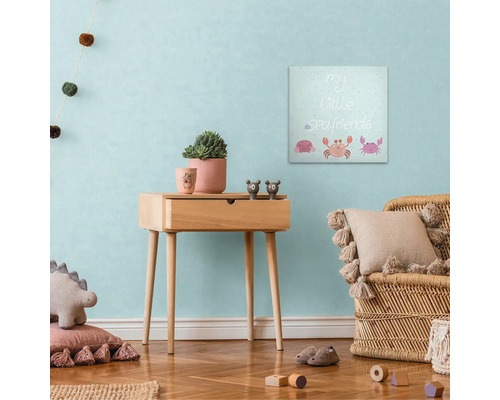 Výzdoba dětského pokoje s plátěným obrazem, odkládacím stolkem a ratanovým křeslem.