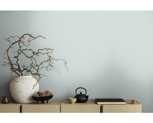 Dekorativní větve ve váze vedle čajové konvice na skříňce