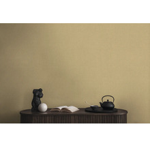 Dekorativní scéna s černou konvicí na čaj, sochou a knihou na skříni před nástěnnou tapetou