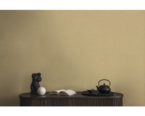 Dekorativní scéna s černou konvicí na čaj, sochou a knihou na skříni před nástěnnou tapetou