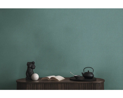 Detailní záběr zelené strukturované tapety nad stolem s dekoracemi.